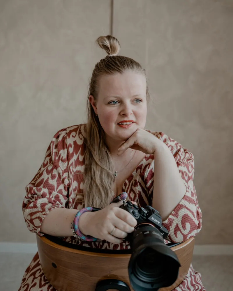 Jolien Norder leunt met haar kin op haar hand, met een Sony-systeemcamera in haar handen